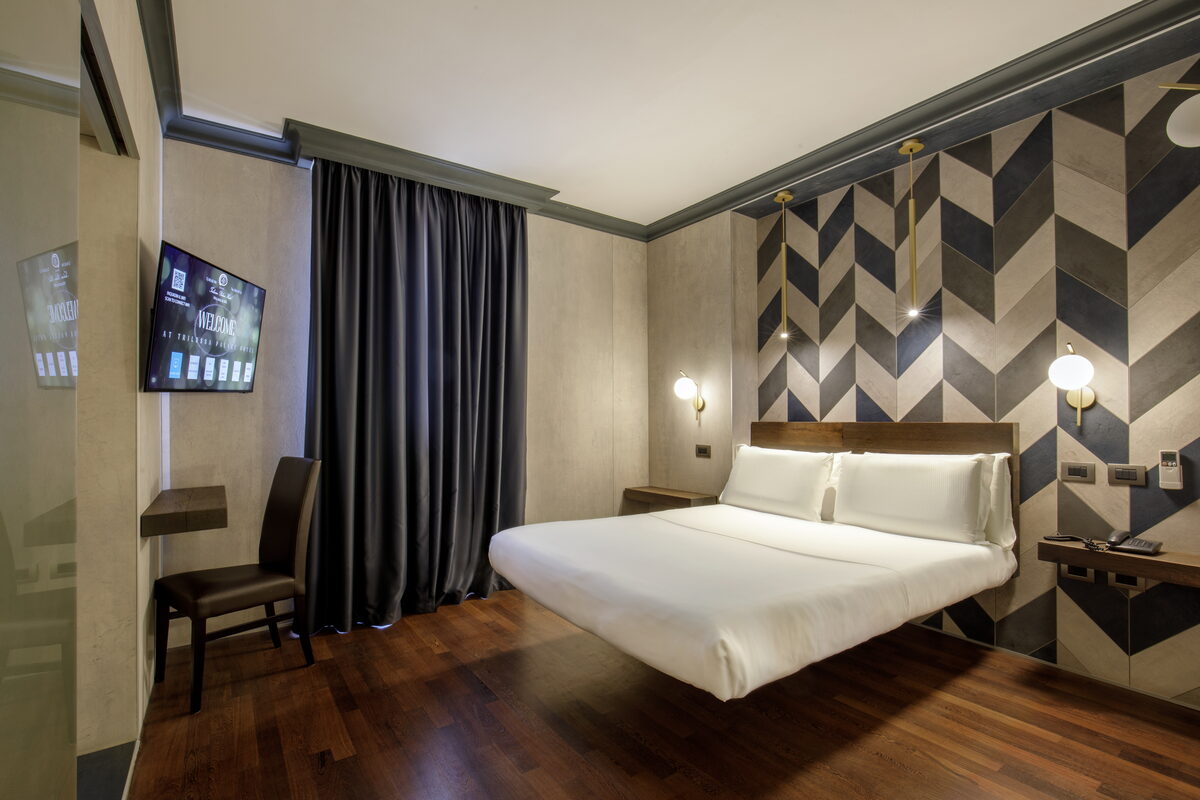 Camera da letto della Suite Wellness 416 con letto king e parete a spina di pesce — Trilussa Palace Hotel Roma