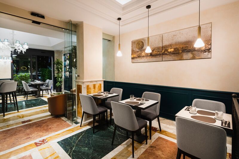 La sala del Ramo Bistrot con lampade a sospensione in ottone, pavimento in marmi policromi e boiserie verde petrolio